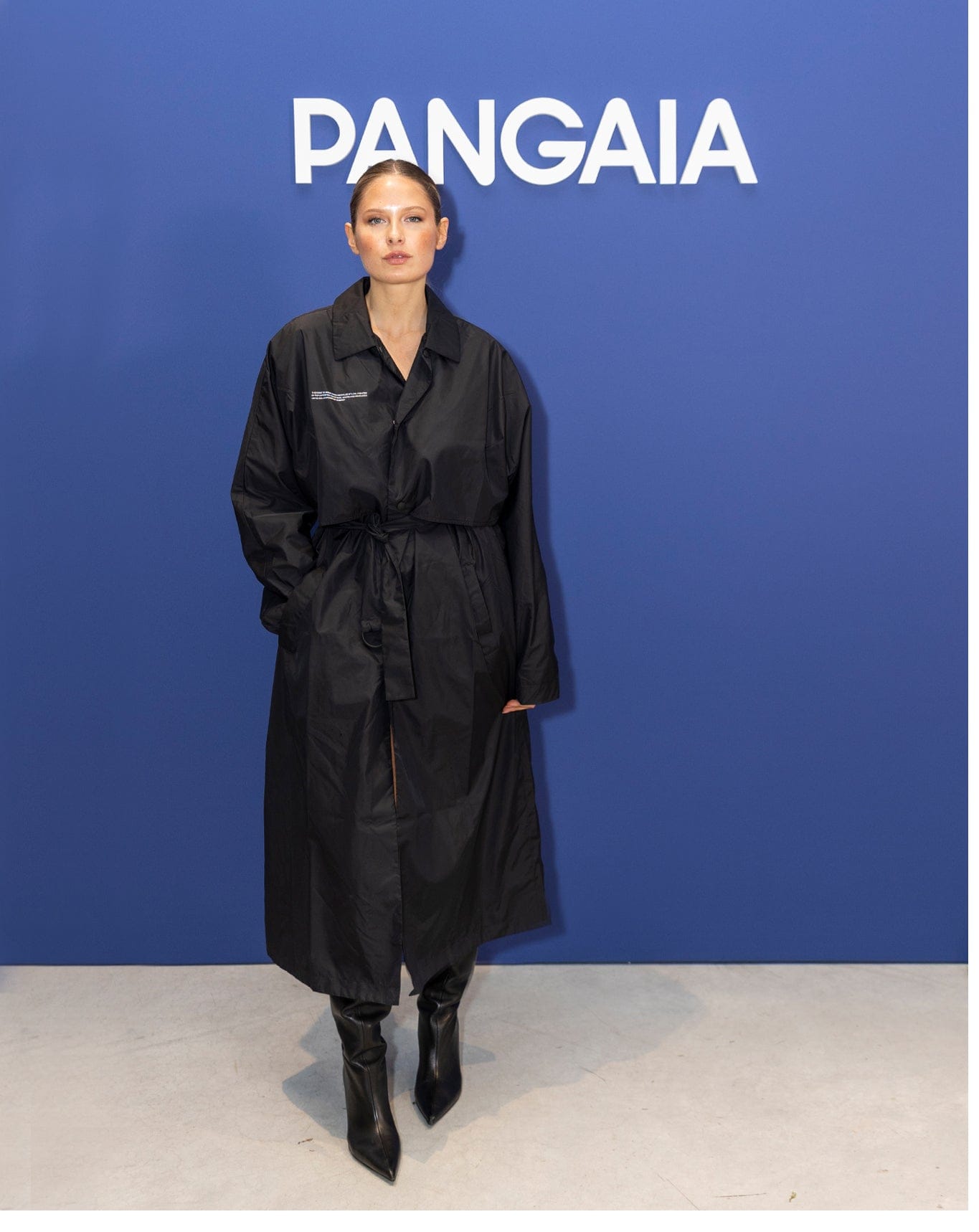 Black oversized technical fabric trench coat on model, featuring a relaxed longline fit, shirt collar, and self-tie waist