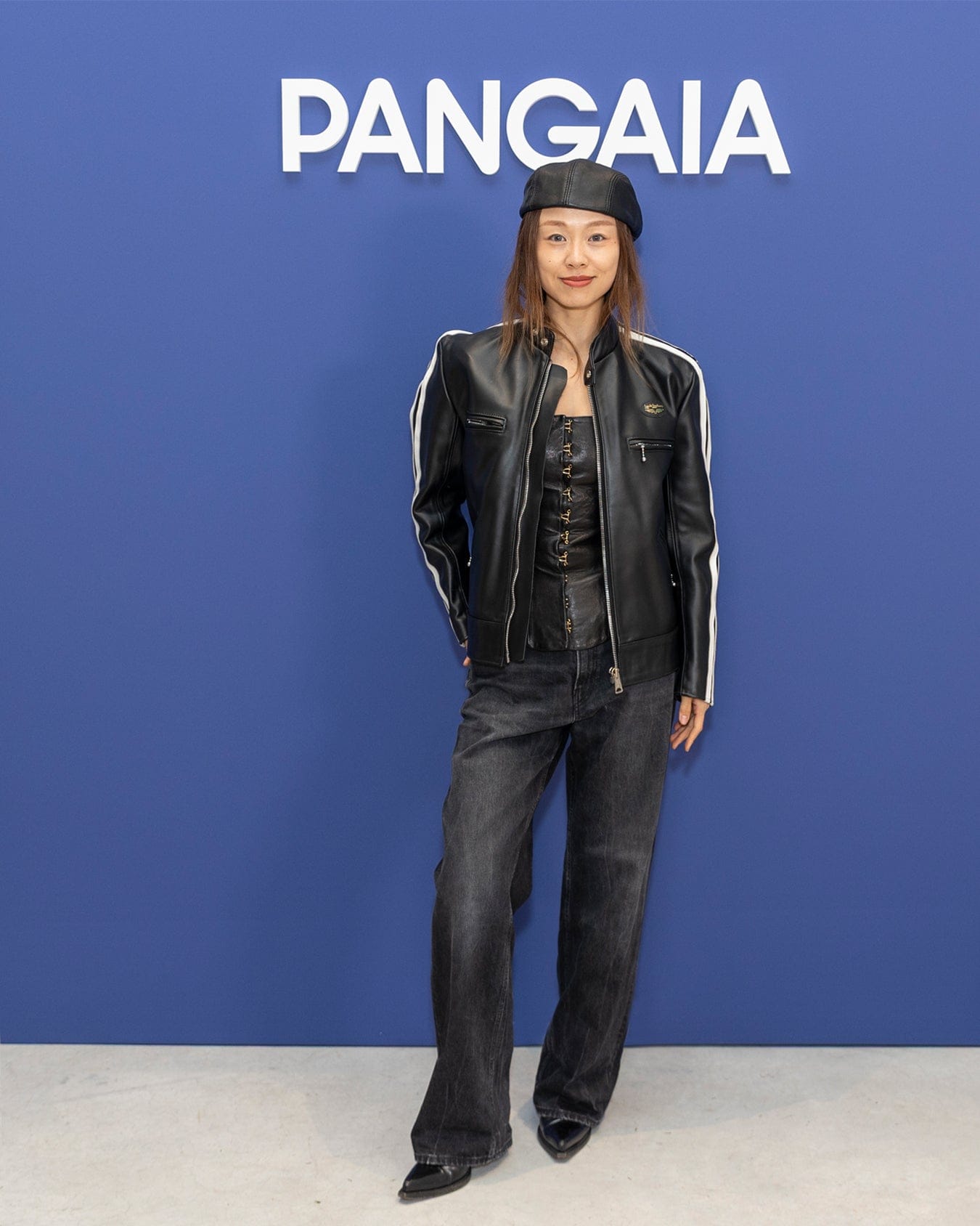 Black leather racer jacket, white sleeve stripes, black corset, dark wash relaxed fit jeans, black leather beret