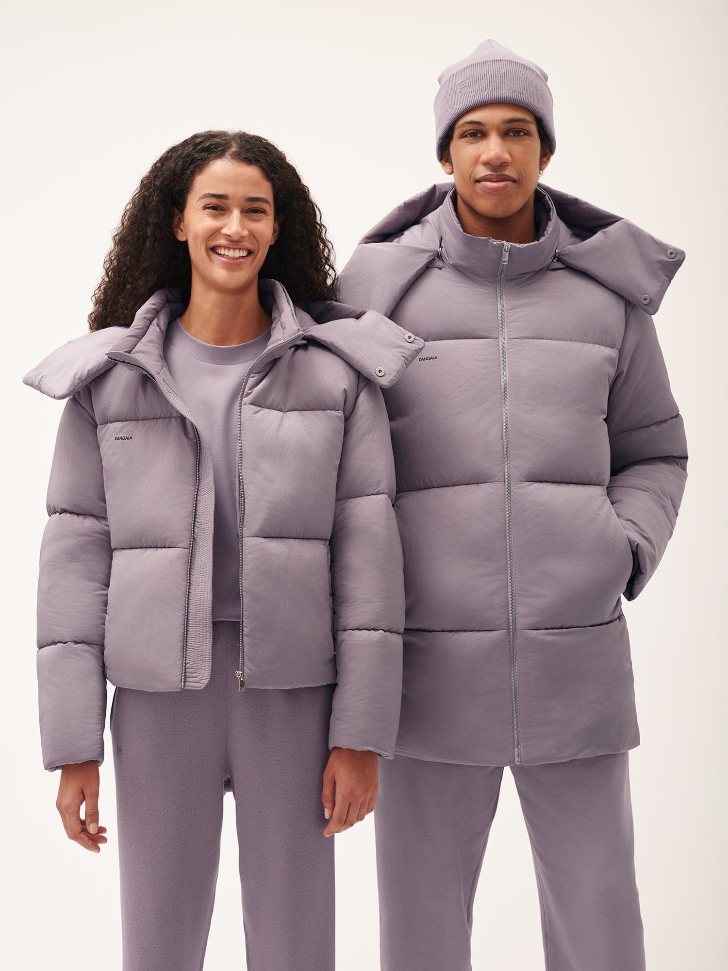Models in matching lavender purple puffer jacket, cropped puffer, long hooded puffer coat, sweatpants, beanie