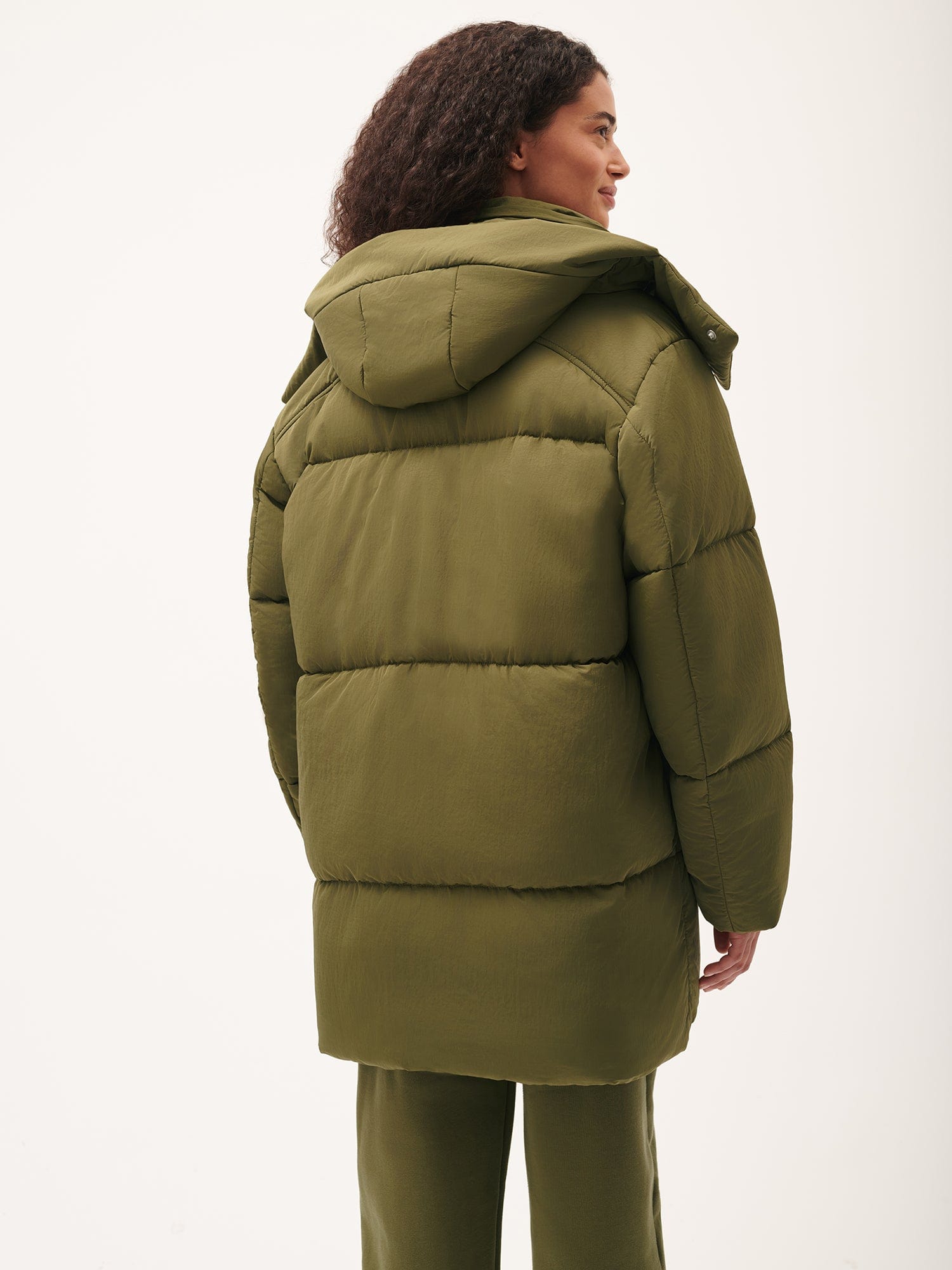 Olive green oversized hooded puffer coat for women. Long padded quilted design with a relaxed fit and textured shell