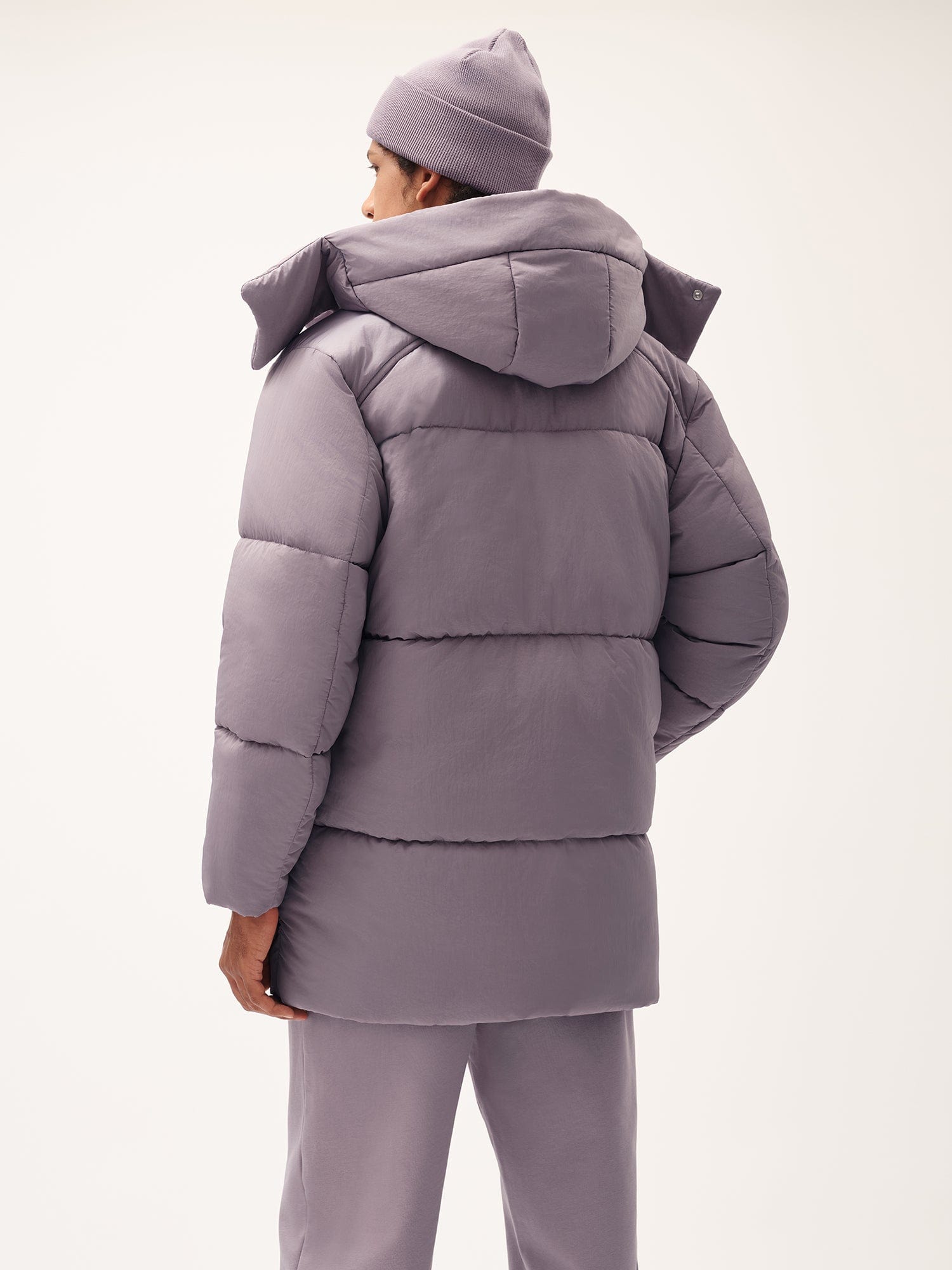 Men's dusty lavender hooded puffer jacket, relaxed fit. Matching ribbed beanie and sweatpants, back view. Warm winter outerwear