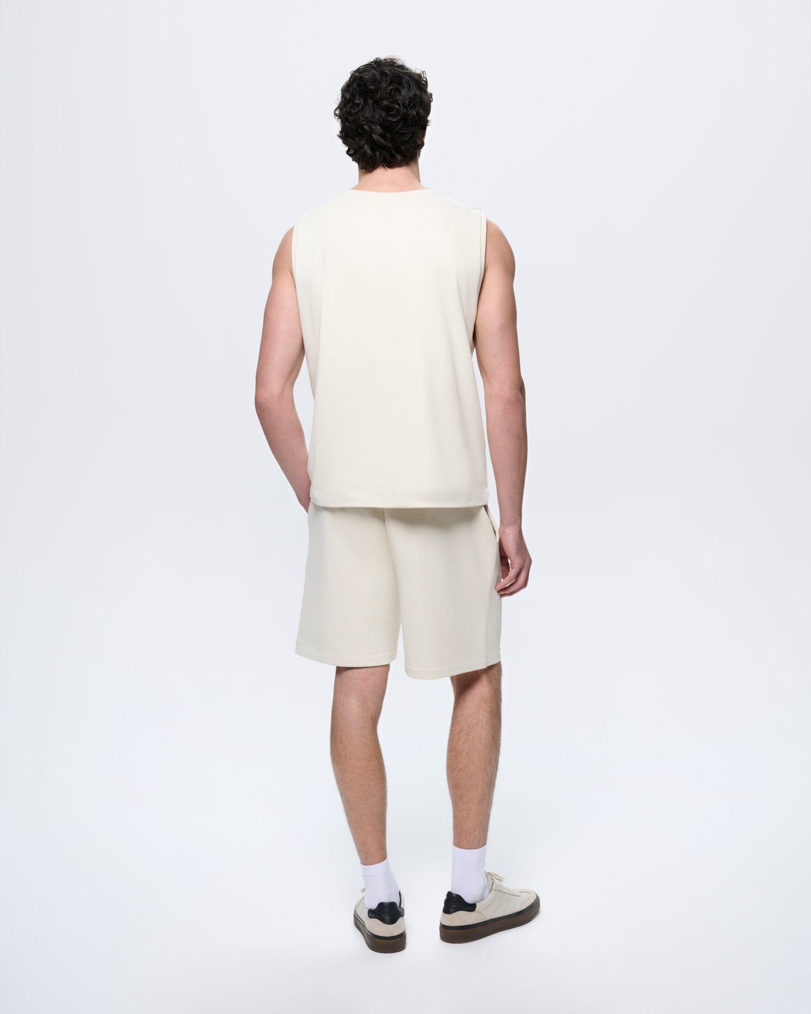 Men's Bone White mid-length organic cotton shorts. Relaxed fit, side pockets, drawstring waist. Model back view