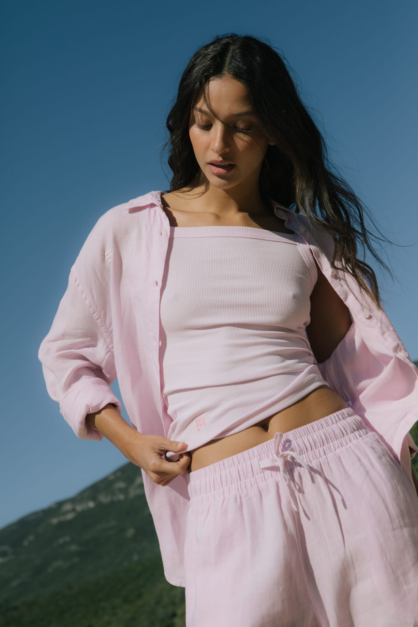 Blush pink ribbed knit camisole, linen oversized shirt, drawstring linen shorts. Relaxed women's resort wear set.