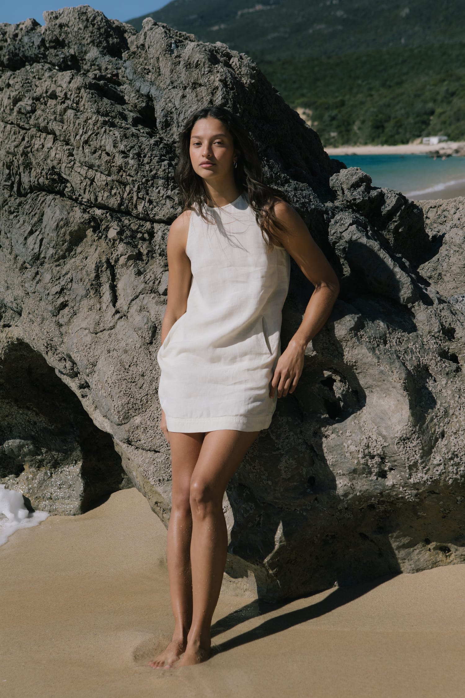 Women's cream linen sleeveless mini dress with side pockets, relaxed fit on beach