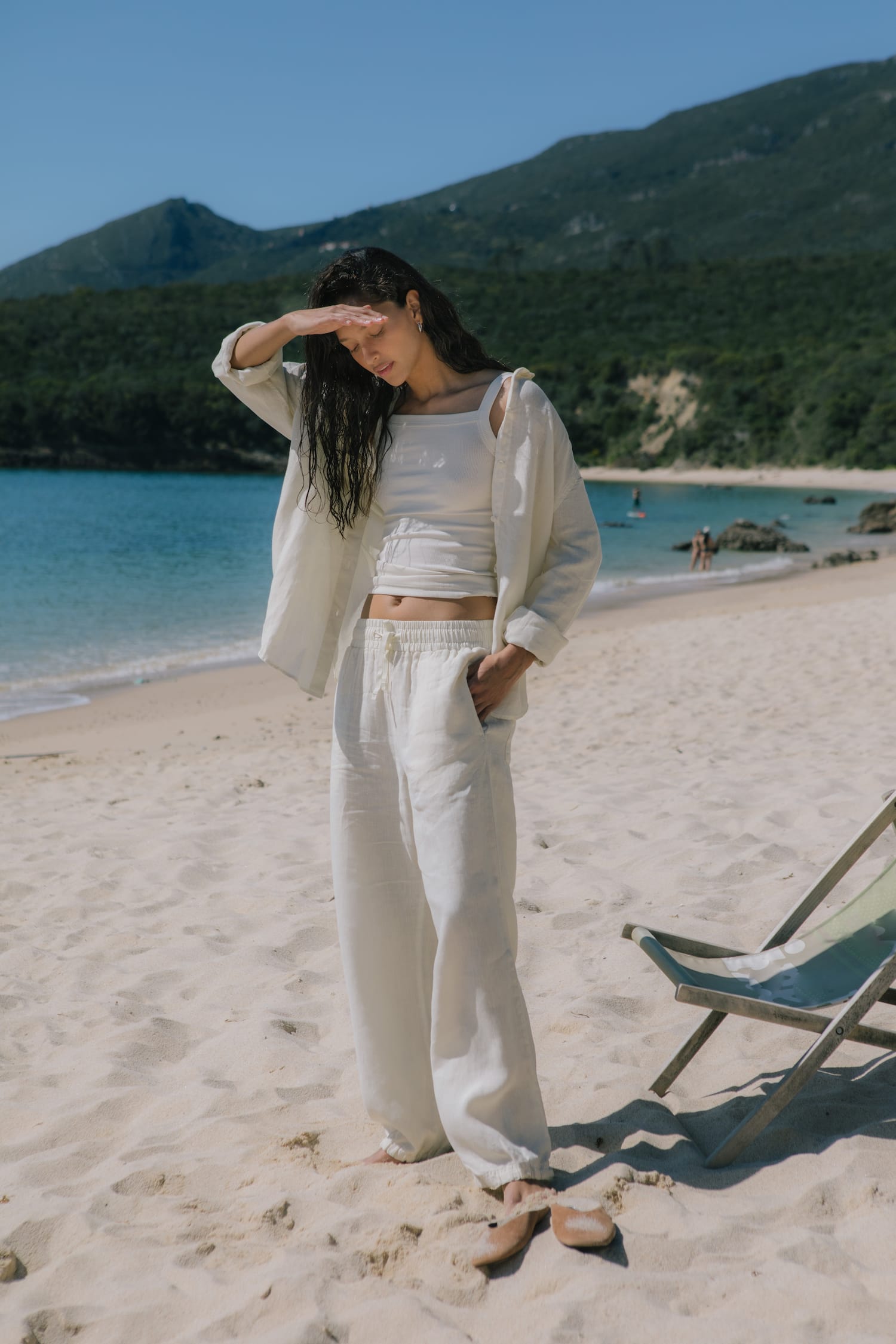 Woman wearing an ecru linen oversized button-down shirt, ribbed crop top, and wide-leg elasticated waist pants
