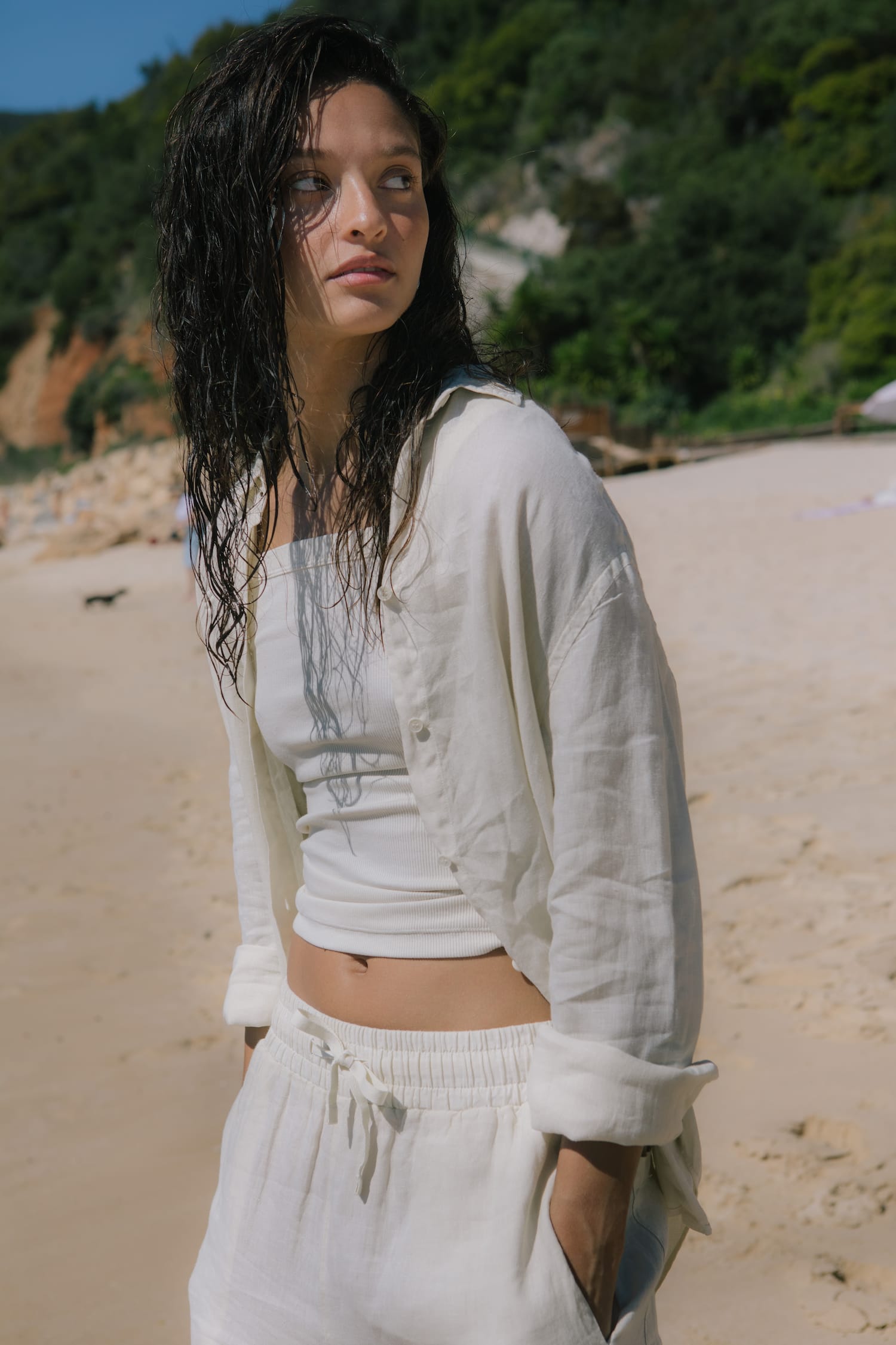 Model in off-white oversized linen shirt, ribbed crop top, and matching linen drawstring shorts. Premium summer resort wear