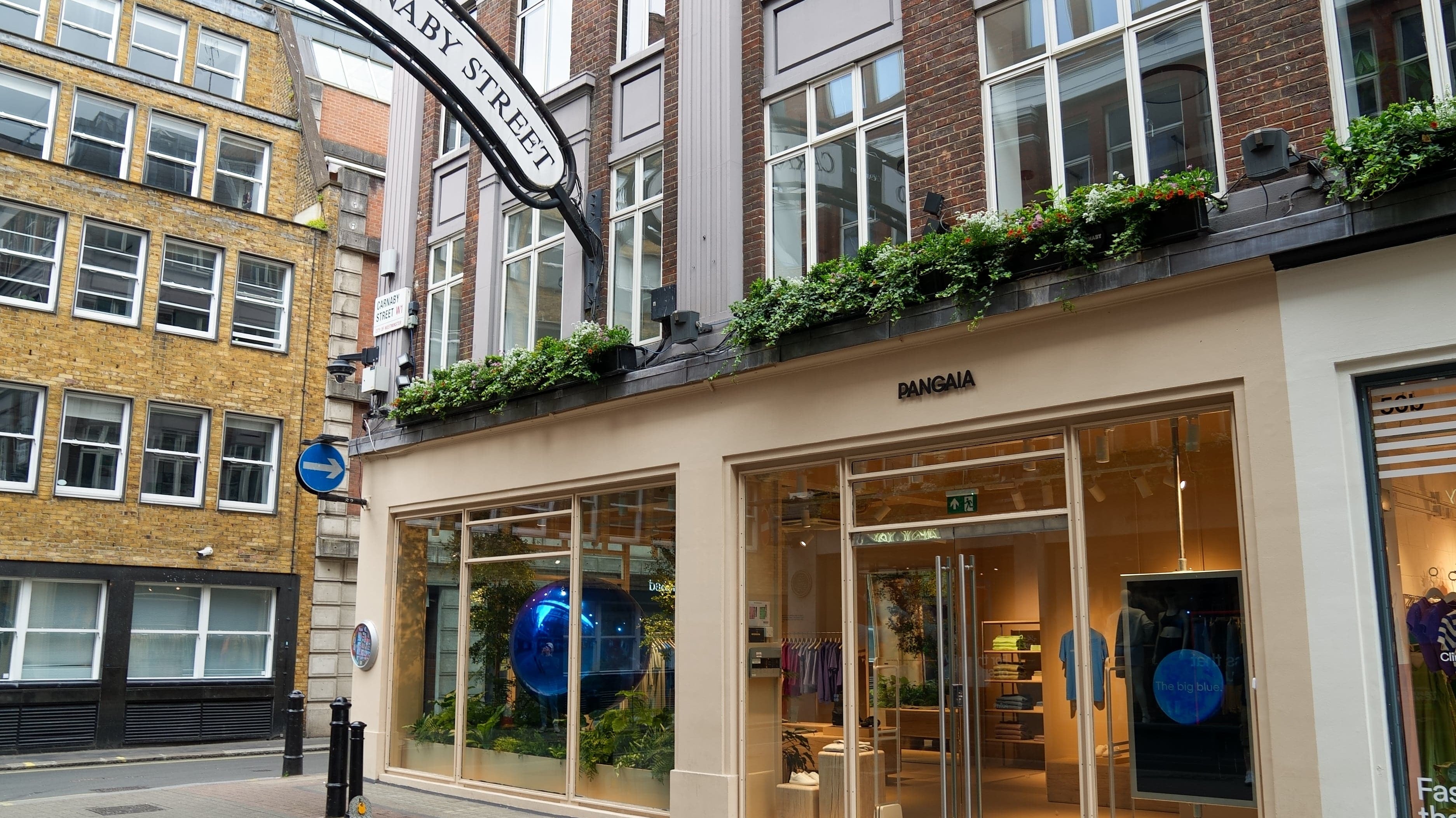 Pangaia retail store on Carnaby Street London. Exterior view showing large windows, colorful clothing displays, and brick buildings