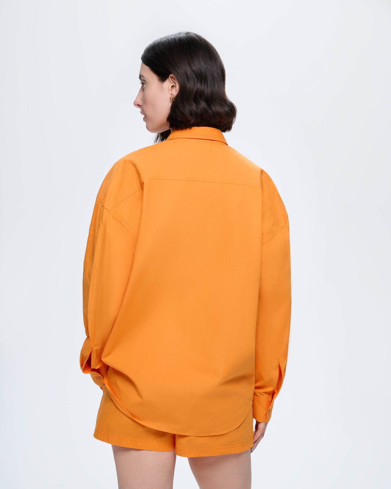 Womens Saffron Orange 100% organic cotton poplin overshirt. Oversized fit shirt on model, back view