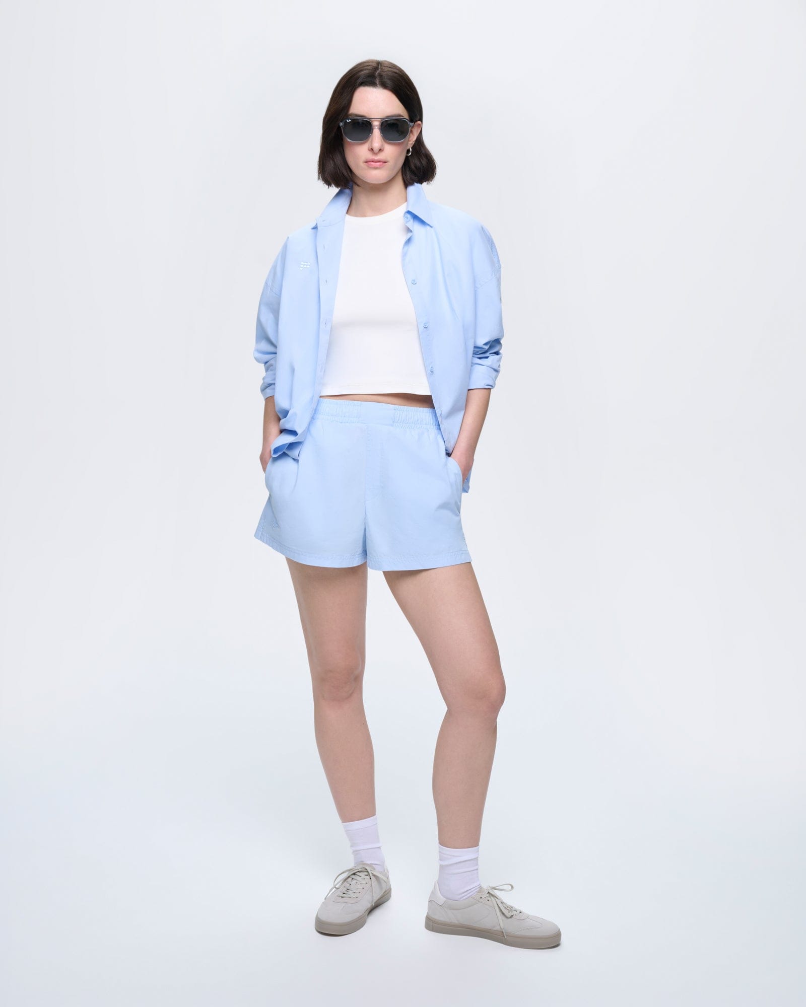 Womens Wildflower Blue organic cotton poplin overshirt, oversized fit, open over white crop top, on model. Buttons, collar, cuffs