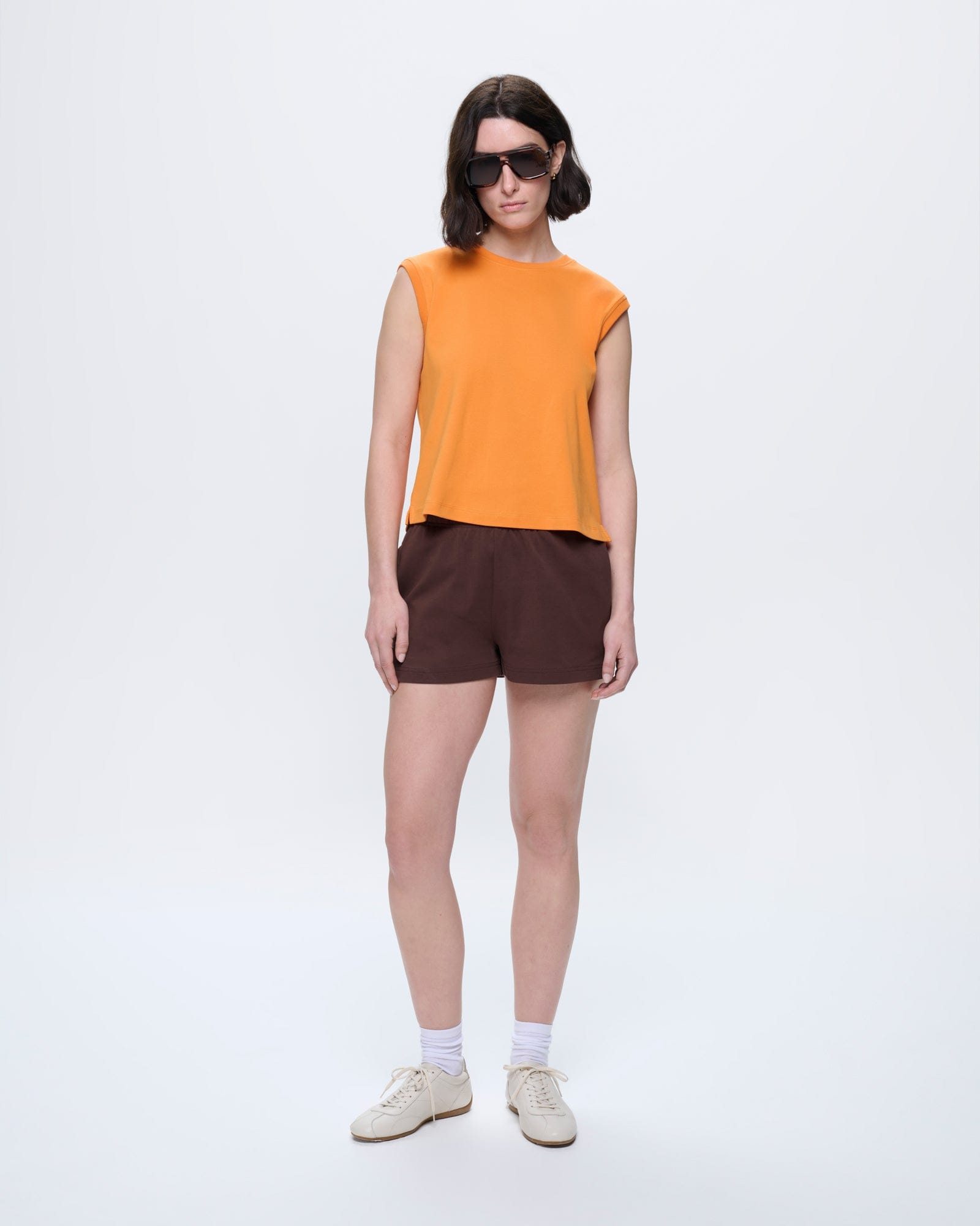 Womens Sleeveless T-Shirt, Saffron Orange. Organic cotton, relaxed fit, crew neck. Model showcases ultra-soft, breathable style