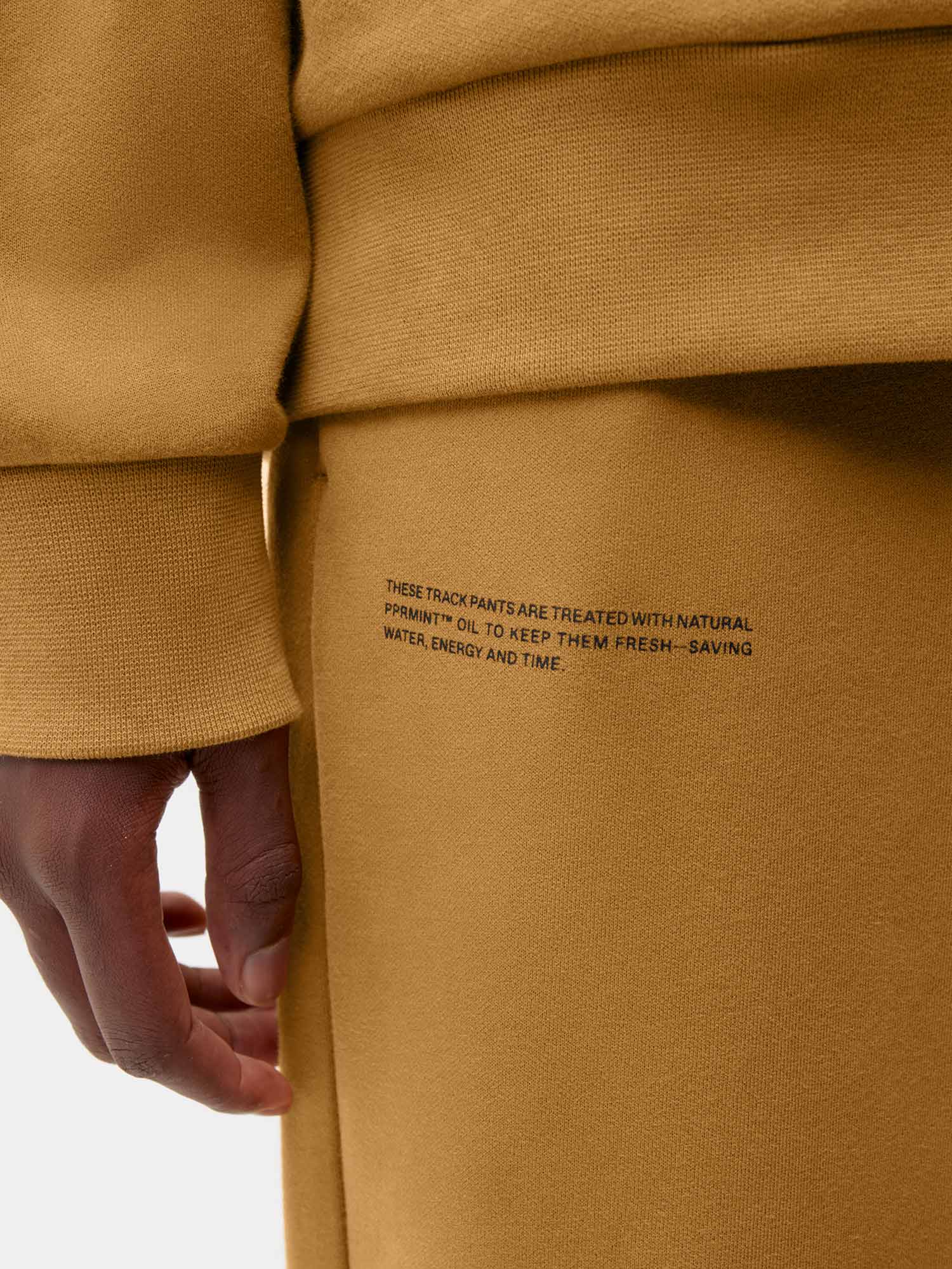 Premium ochre cotton track pants, ribbed cuffs, with black text detailing PPRMINT™ treatment on thigh