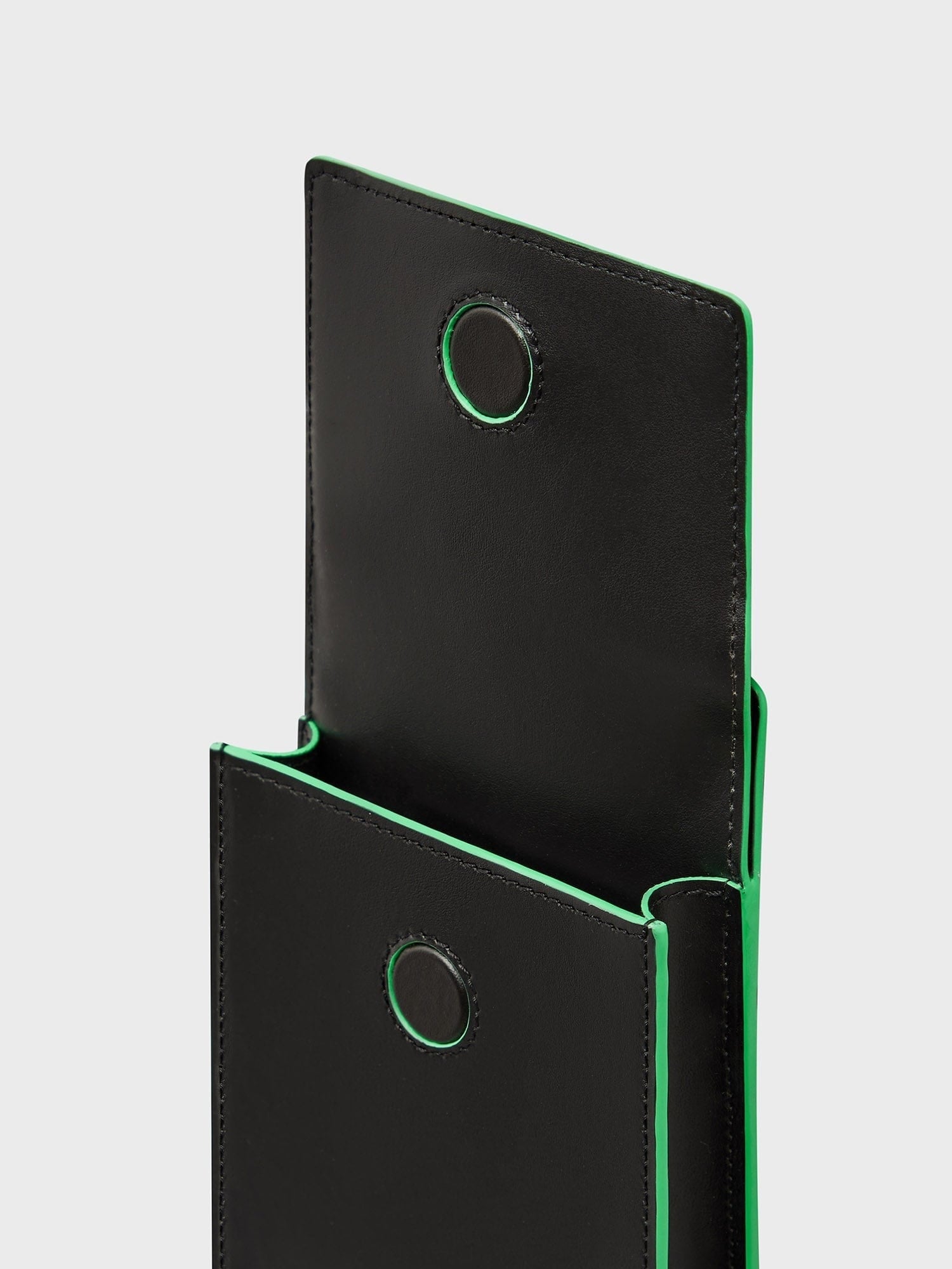 Open Biobased Passport Holder packshot. Black plant-based leather alternative, jade green trim, circular eyelets